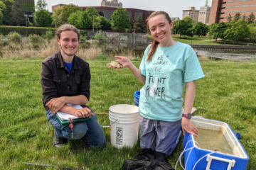 Two students holding a fish they have caught and measured