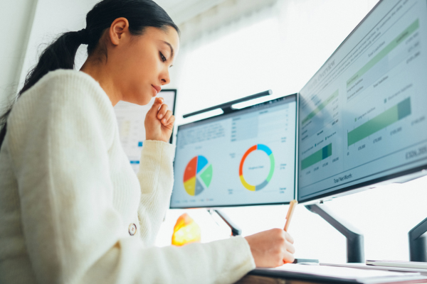 A woman sitting a desk of computer monitors