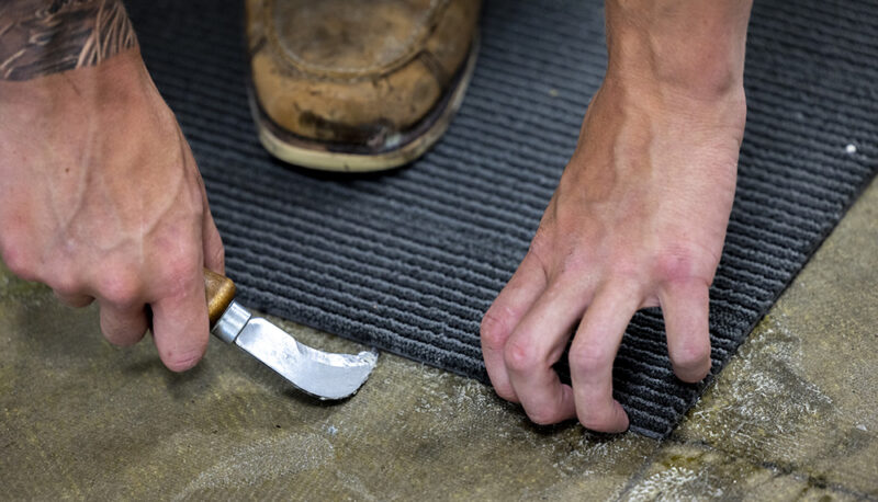 A closeup of a worker laying carpet