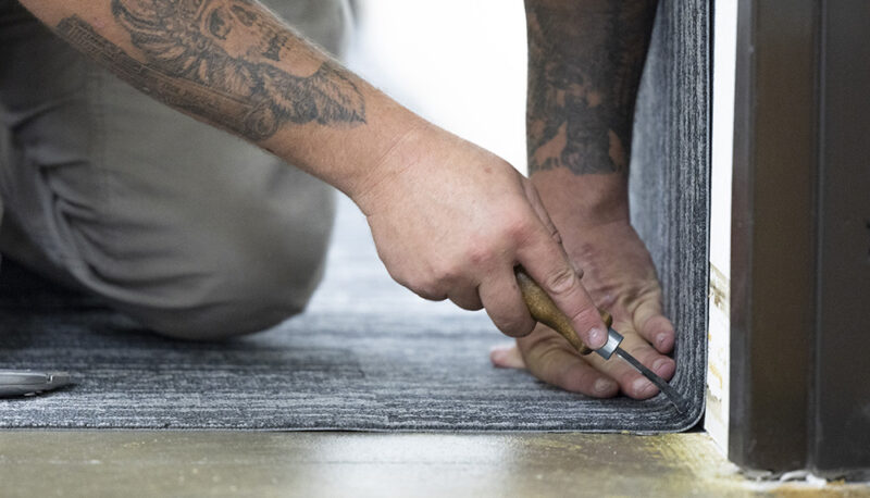 A closeup of a worker laying carpet