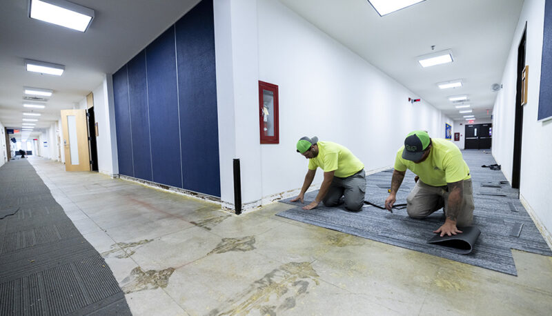 Two workers laying carpet