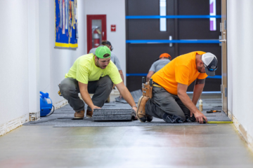 Two workers laying carpet