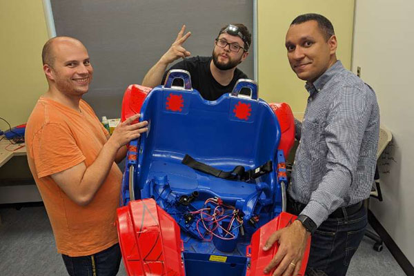 Christopher Williams, Matt Roome and assistant professor Thiago Ferreira work on the Power Wheels.