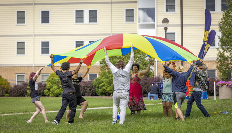 Students playing with a rainbow tarp