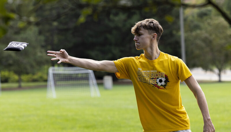 A student throwing a cornhole bag