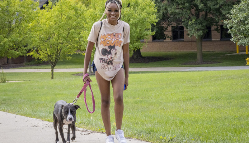 A student walking with her dog on a leash