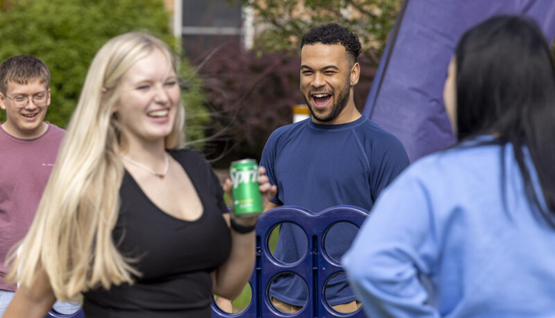 Students laughing around a big Connect 4 game.