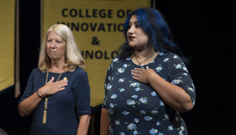 Two women holding their hands to their hearts on stage.