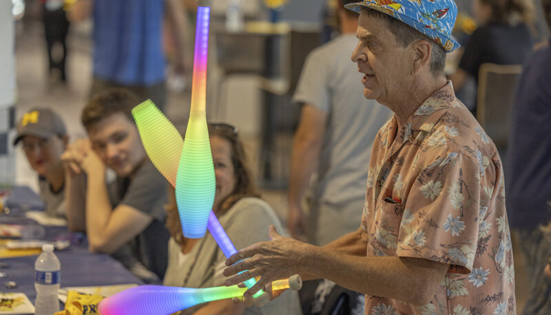 A juggler juggling light up bowling pins.