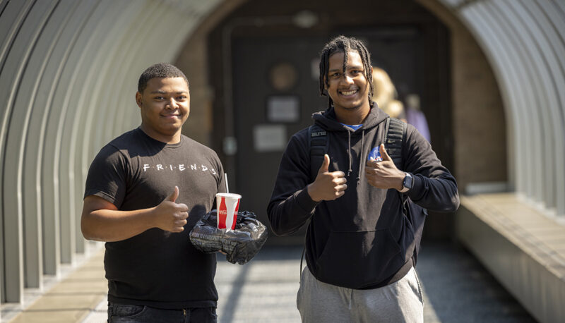 Two students giving a thumbs up in a Skywalk