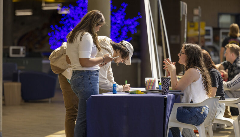 Students talking to organization members sitting at a tabe in the UCEN