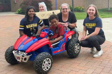 UM-Flint students Shalini Augenstein (left), Marwa Hammami, professor Donna Case and student Elizabeth Mansfield pose with Flint's Kaden Stevenson, who they recently adapted a power wheels car for