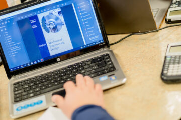 A UM-Flint student types at a PC laptop.