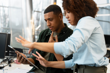 A man and woman looking at a tablet screen in a modern office