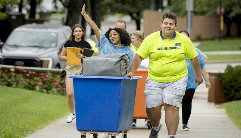 Students pushing a cart of items into First Street