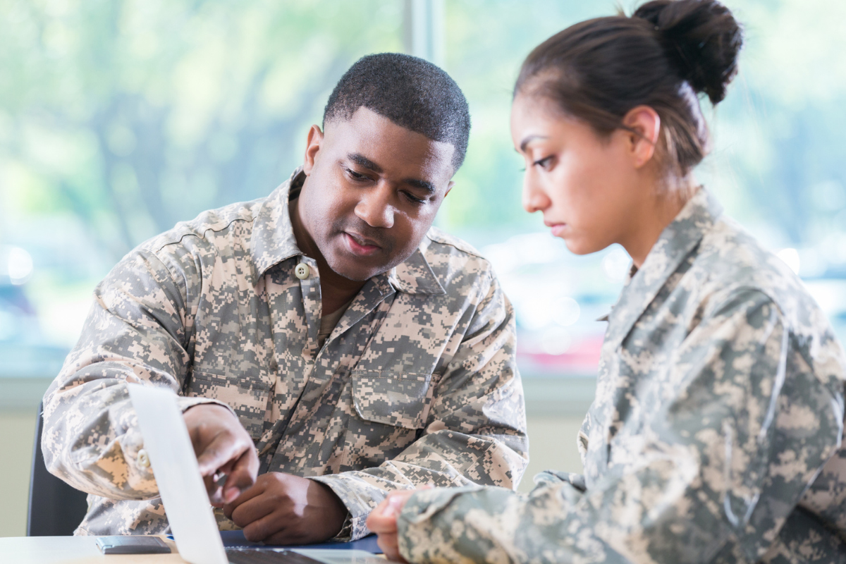 A man and woman in military uniforms sitting at a desk.