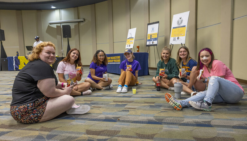 Students sitting on the ground smiling