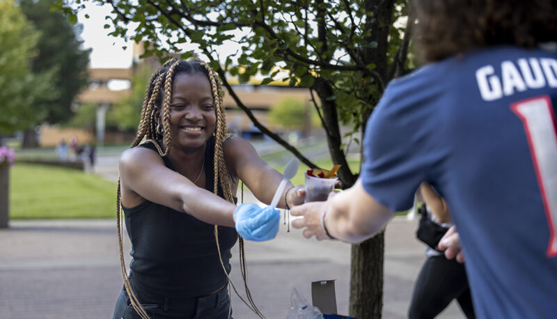 A student handing out ice cream outside.