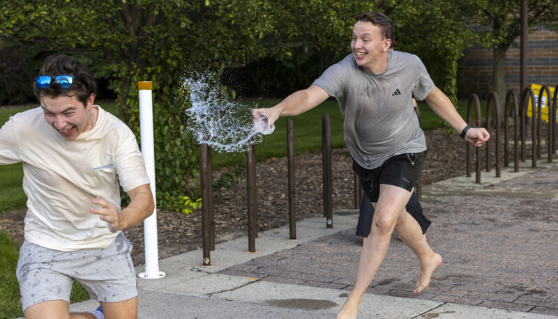 One student chasing the other with water