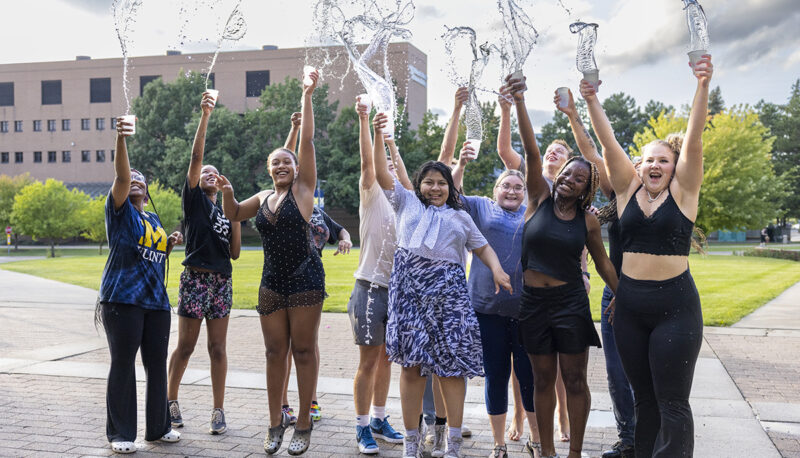 A group of students jumping in the air after a water fight