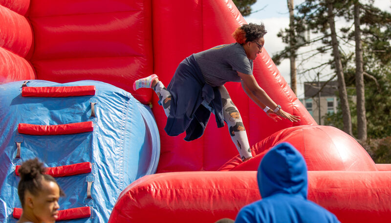 A student jumping off an inflatable carnival game