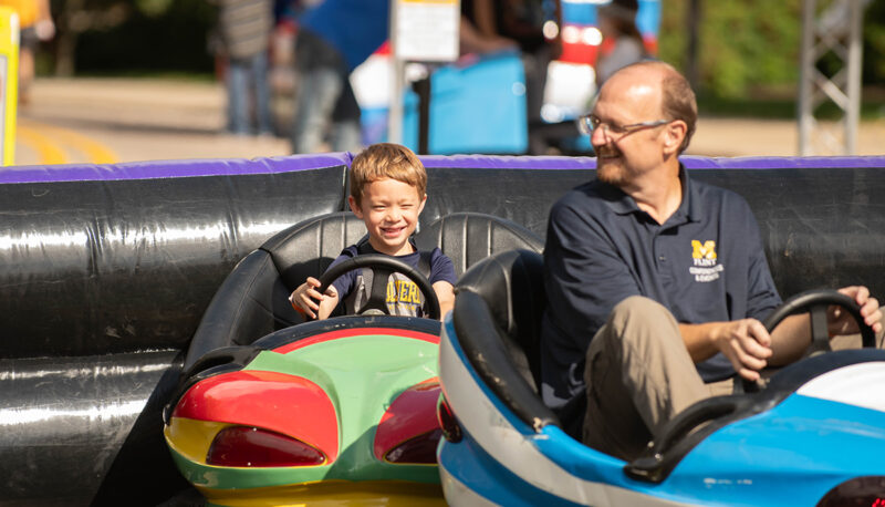 A staff member and young child on bumper cars