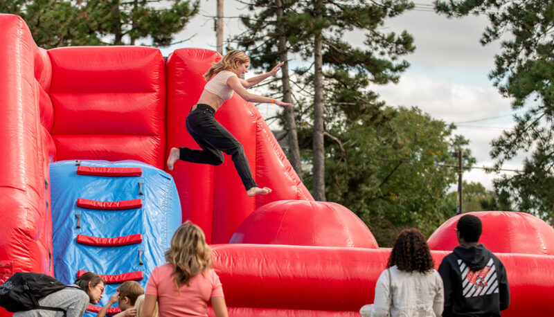 A student jumping off an inflatable carnival game