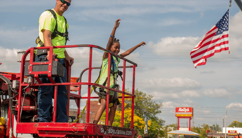 A kid in a cherry picker basket with operator