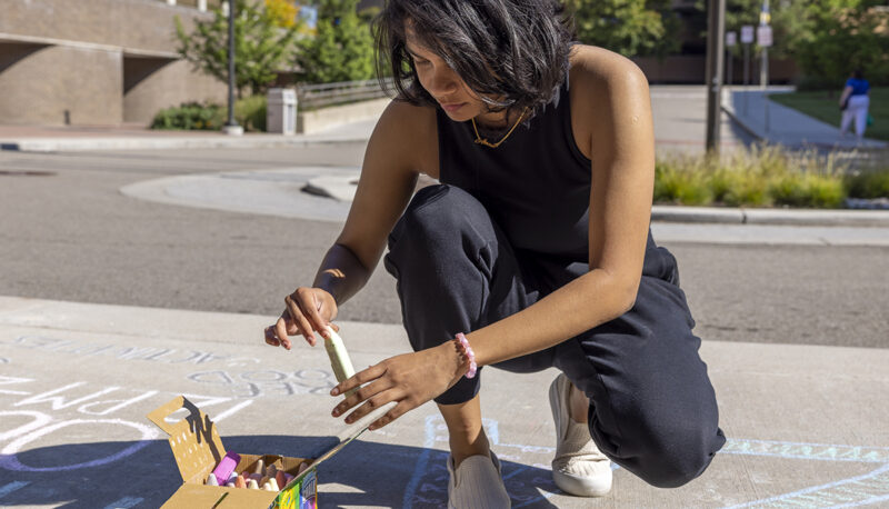 A student using sidewalk chalk at Eco Extravaganza