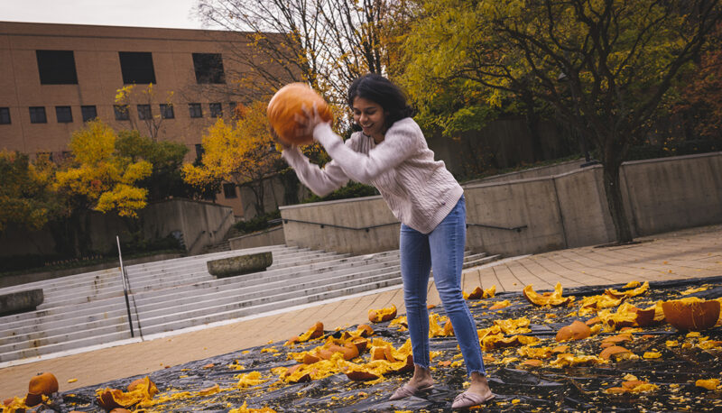 A student smashing a pumpkin