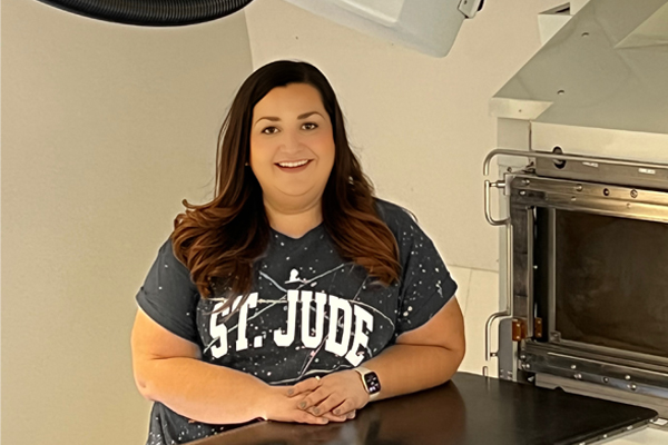 Laura Jolovic poses with radiation therapy equipment at her job at St. Jude Children's Research Hospital