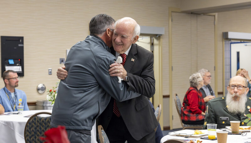 Two individuals hugging during the Veterans Day reception