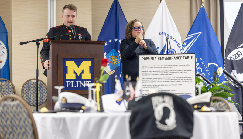 A student veteran in a dress Marine Corps uniform speaks at a podium