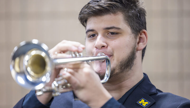 A UM-Flint student plays Taps on the trumpet