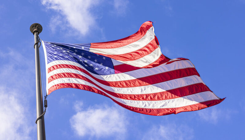 An American Flag flying against a blue sky