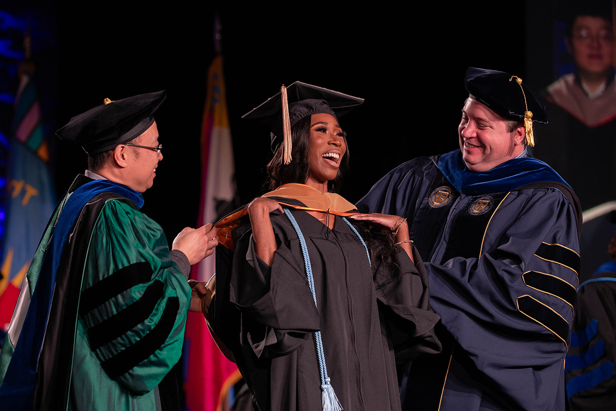 A student receiving graduation regalia on stage