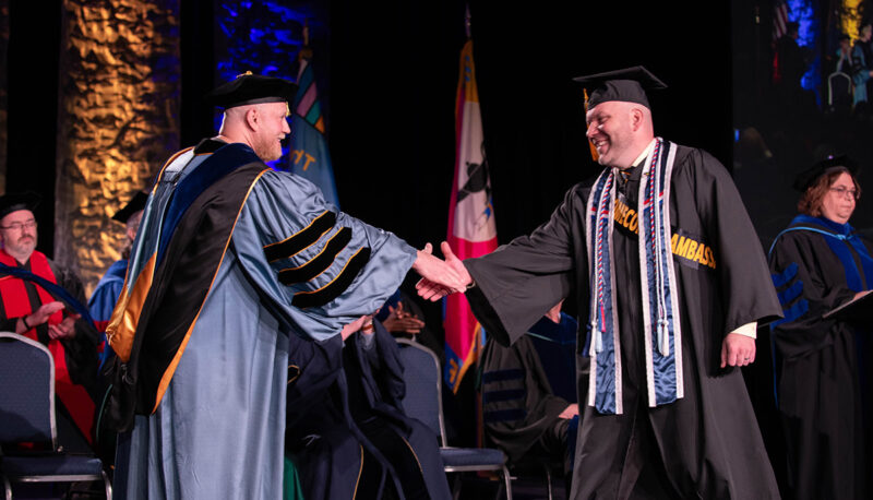 A student shaking hands with Yener Kandogan