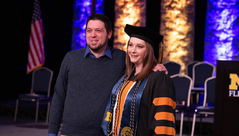 A student posing with a man for a photo