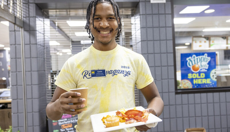 A student posing for the camera with a plate of food