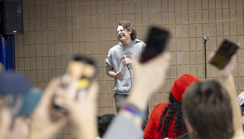 A crowd watching a student sing karaoke