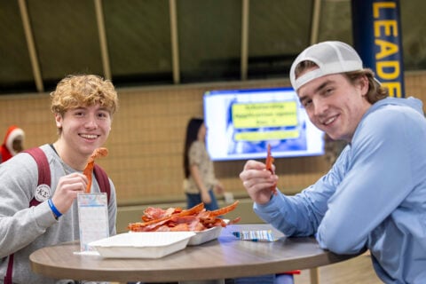 Students posing with a plate of bacon
