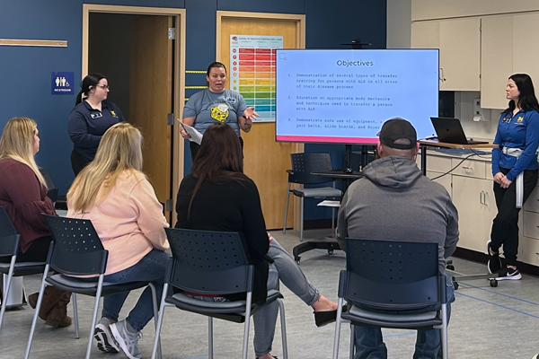 Three students talk to a group of participants during the ALS caregiver lab.