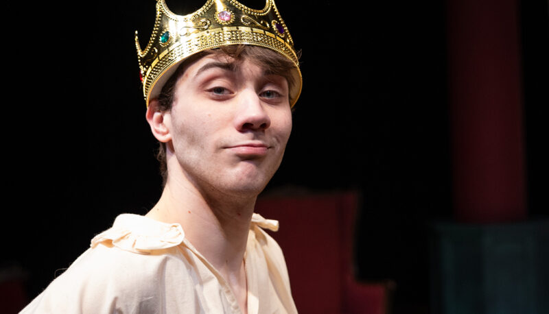 Students performing Shakespeare. Man wearing a crown