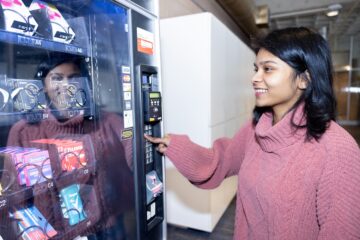 A UM-Flint student accesses the new health and wellness vending machine installed in the second floor of the UCEN.