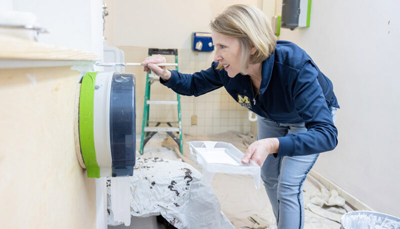 A UM-Flint faculty member painting a wall.