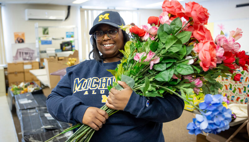 A UM-Flint student smiling with a bouquet of flowers