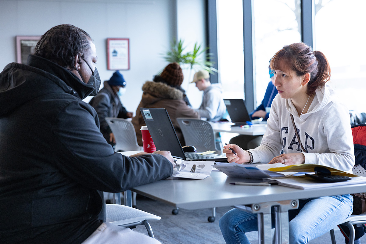 A female UM-Flint alumni talking with a tax prep client