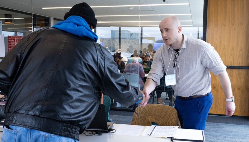 A student shaking hands with a tax prep client.