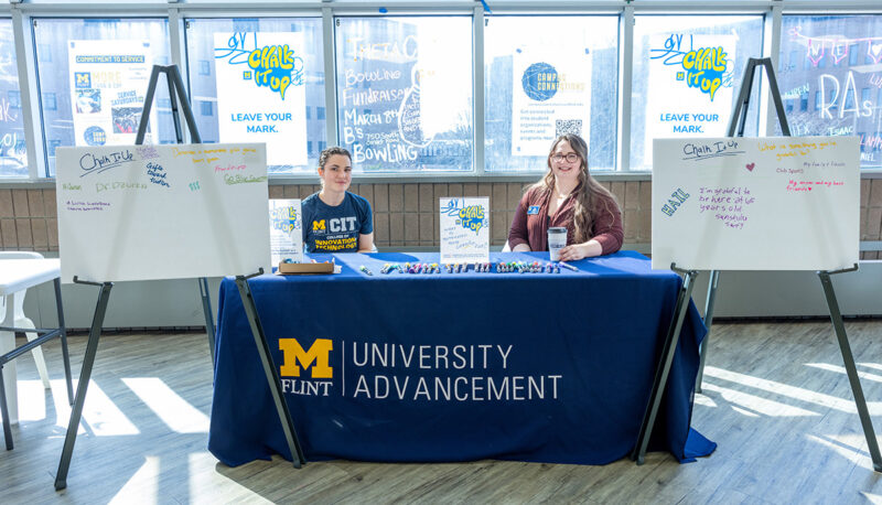 Two staff members sitting at an University Advancement table