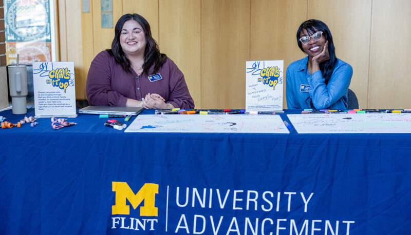 Two staff members sitting at a University Advancement table